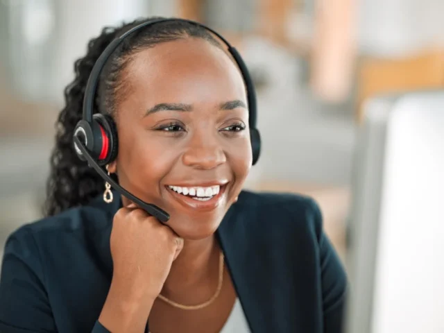 Smiling US-based receptionist wearing headset, answering calls for clients of ReceptionHQ's reliable virtual receptionist services